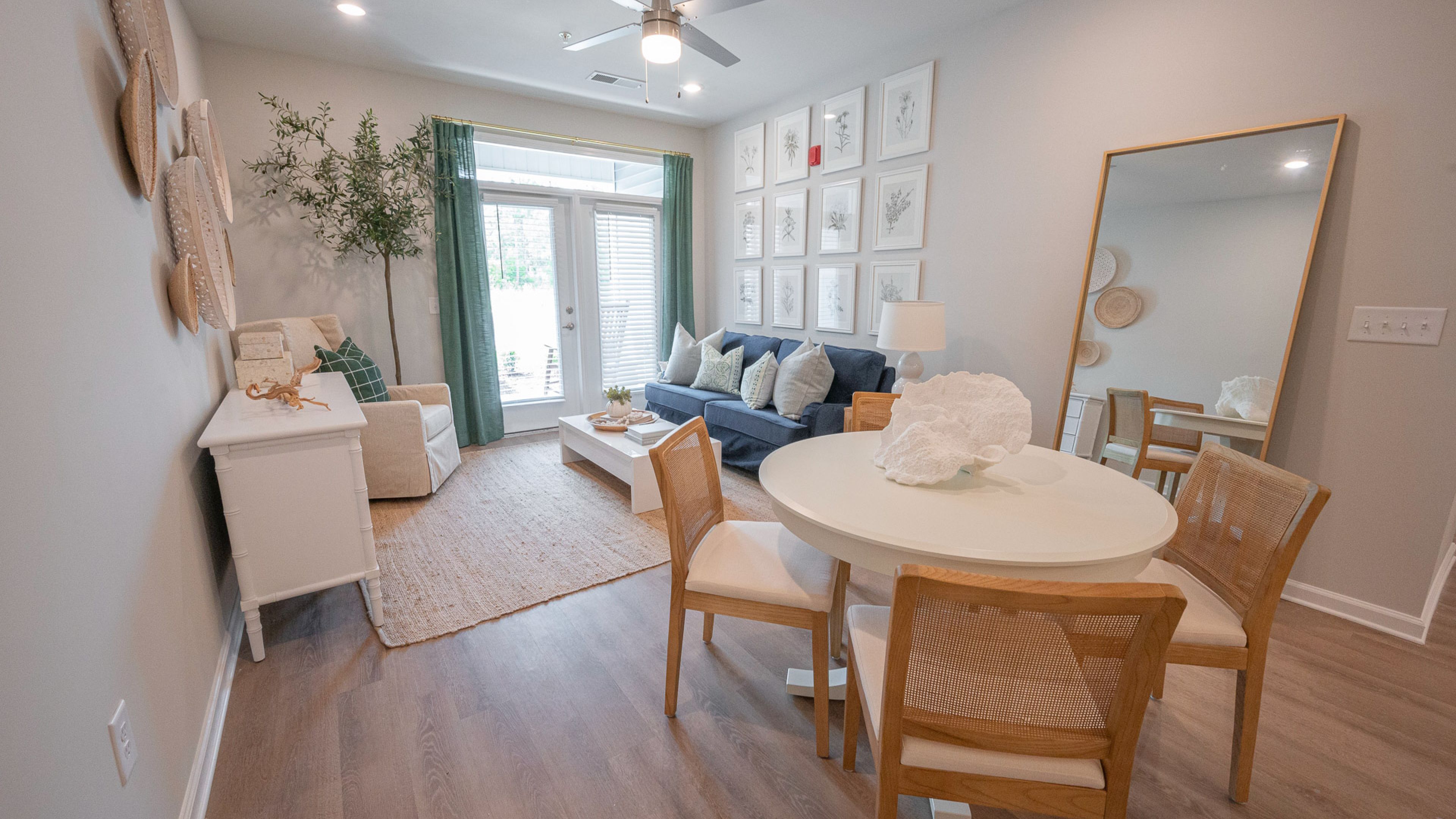 Hawthorne Waterside cozy living space with a plush sofa, gallery wall of white frames, and a round dining table set.